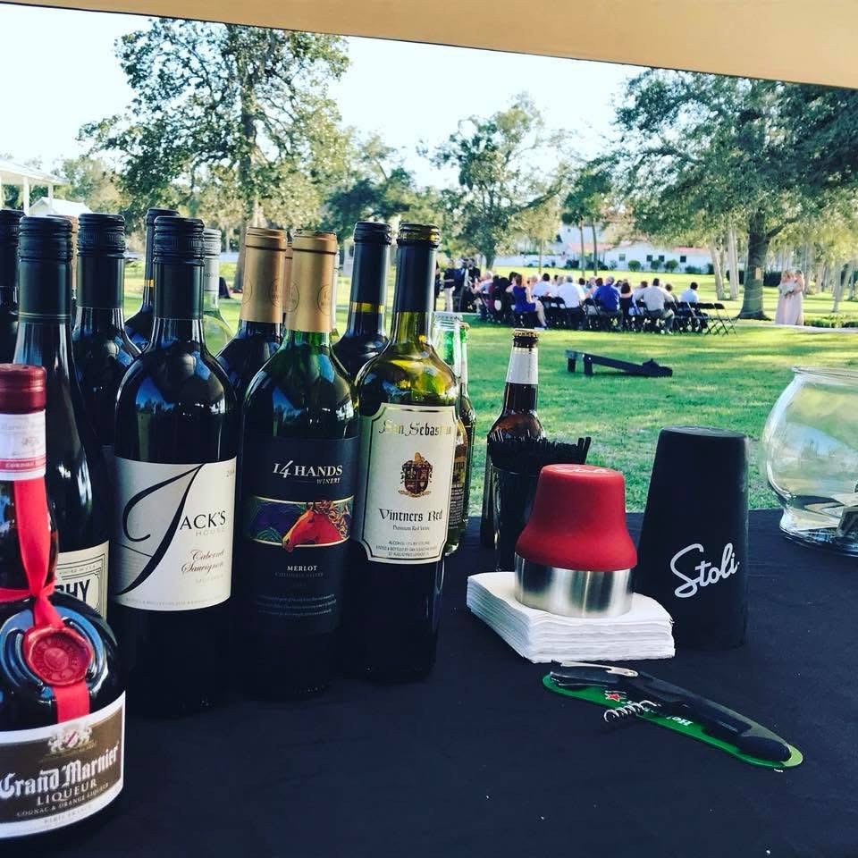 Wine and spirits set up on an outdoor bar at a lawn wedding